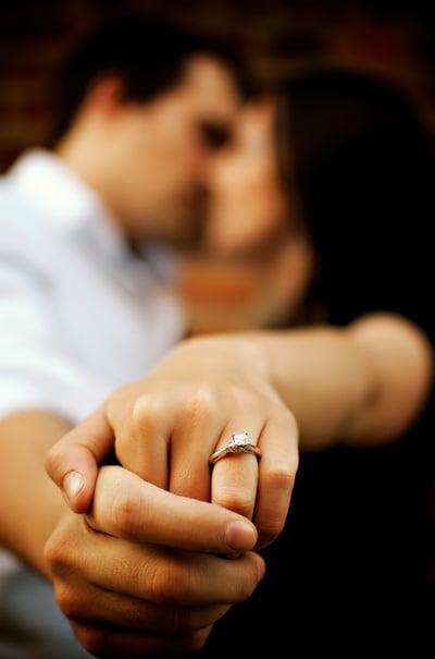 Couple kisses as they show off engagement ring